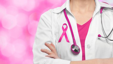 Kadın doktor göğüs renk arka plan üzerinde pembe kurdele ile. Onkoloji ve meme kanseri kavramı.
