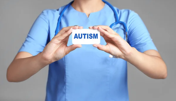 Концепція дитячого аутизму. Руки лікаря тримають карту на сірому фоні — стокове фото