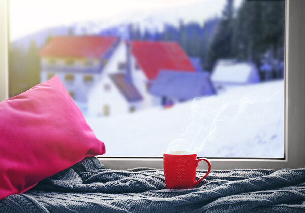 Cup of hot drink on the windowsill in winter landscape background