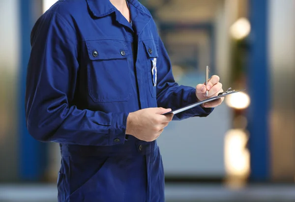 Monteur in uniform met een Klembord en pen op de achtergrond wazig benzinestation — Stockfoto