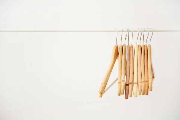 Cabides de revestimento de madeira em trilhos de roupas e fundo branco — Fotografia de Stock