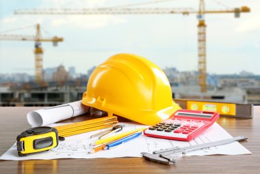 Construction blueprints with tools and helmet on building construction background