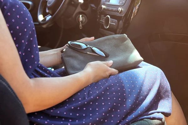 Дівчина з сумкою і сонцезахисними окулярами в машині — стокове фото