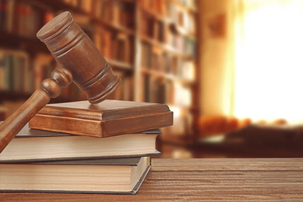 Gavel with sound block on bookshelf in library background — Stock fotografie