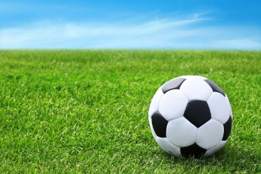 Futbol topu yeşil çim ve mavi gökyüzü arka plan