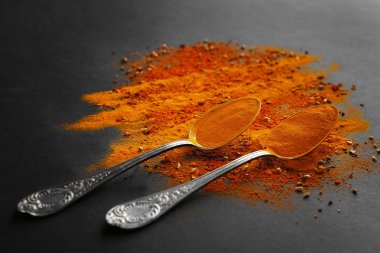 Karanlık bir arka plan üzerine kaşık içinde baharatlar