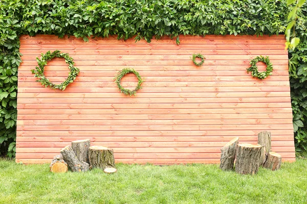 芝生の上に緑の花輪で飾られた木製の壁 — ストック写真