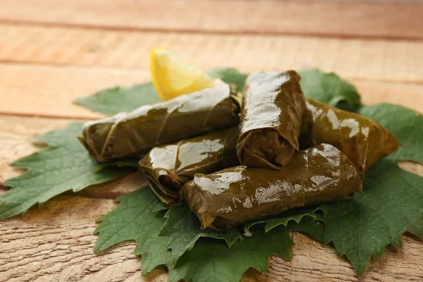 Gevulde heerlijke Dolma met citroen op vine blad en houten achtergrond — Stockfoto