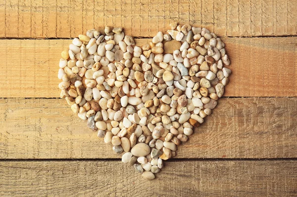 Piękne serce z drobnego żwiru na podłoże drewniane — Zdjęcie stockowe