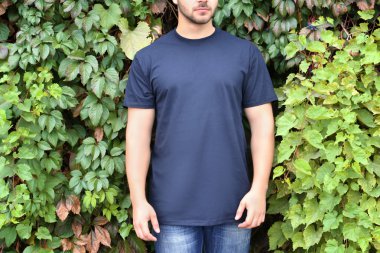 Boş t-shirt üzerine yeşil yaprakları arka plan, closeup genç adam