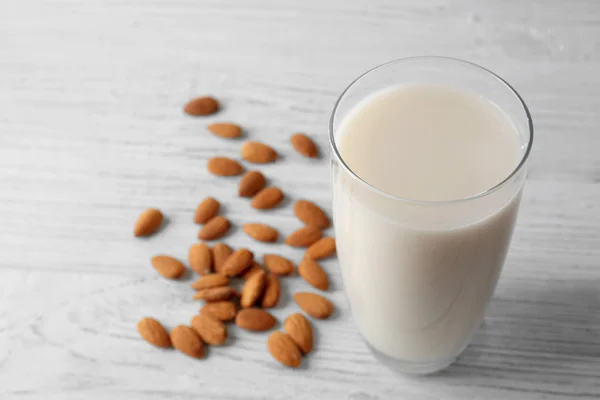 Vaso de sabrosa leche de almendras sobre mesa de madera blanca, vista de cerca — Foto de Stock