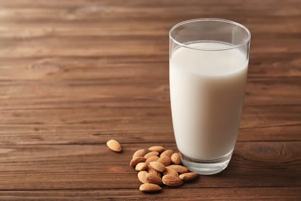 Glas leckere Mandelmilch auf Holztisch — Stockfoto