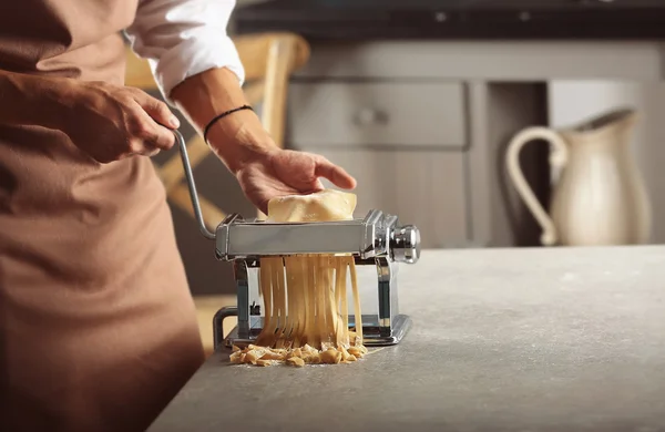 Man using pasta machine to prepare tagliatelle, close up view — Stock Photo, Image