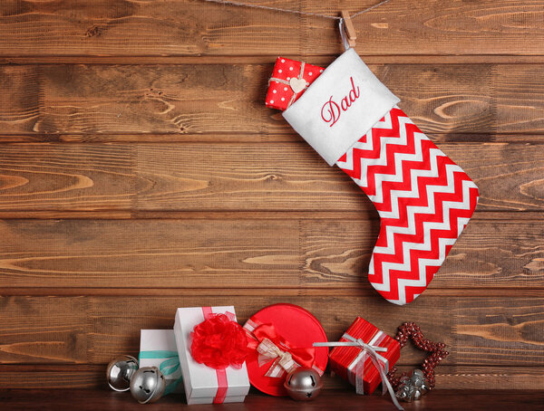 Christmas stocking and presents against wooden wall