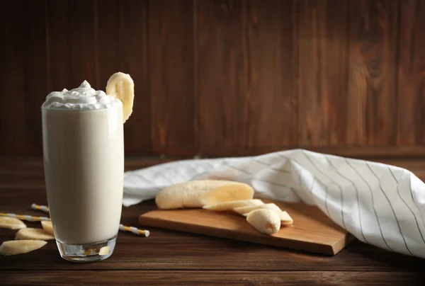 Delicioso milkshake com banana em fundo de madeira — Fotografia de Stock