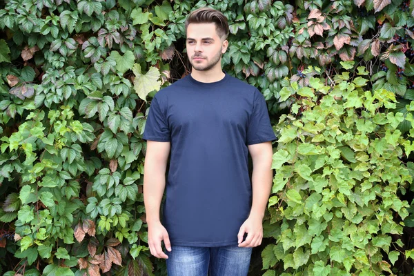 Jonge man in lege t-shirt op groene bladeren achtergrond — Stockfoto