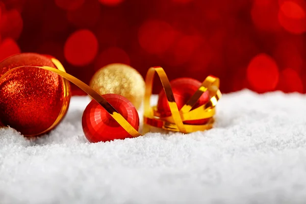 Close up view of beautiful Christmas baubles and ribbon on white snow against defocused lights — Stock Photo, Image