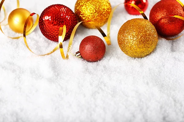 Vackra julgranskulor och band på vit snö, närbild — Stockfoto