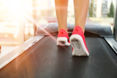 Legs of sporty woman running on treadmill in gym, close up view clipart
