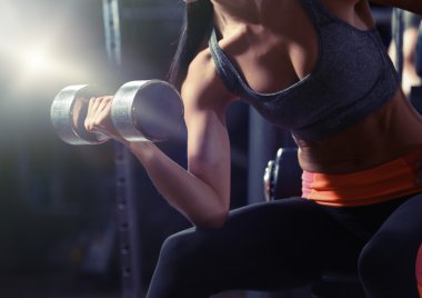 genç kadın dumbbell içinde jimnastik salonu ile kasları esneme