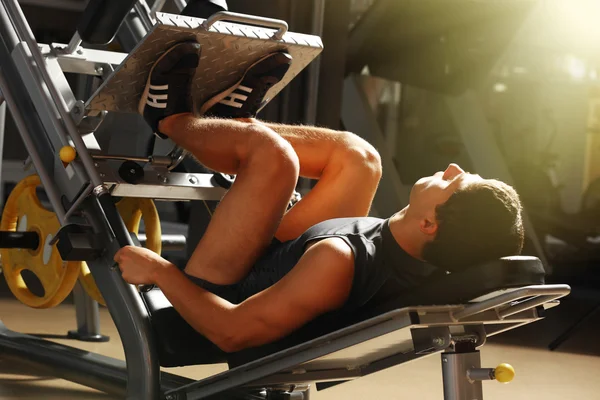 Atletisk man flexar muskler på maskin i gymmet — Stockfoto