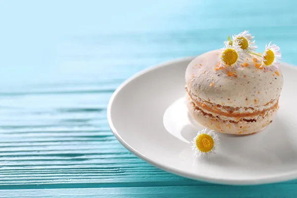 Sabroso macarrón y flores en plato blanco sobre fondo de madera azul claro — Foto de Stock