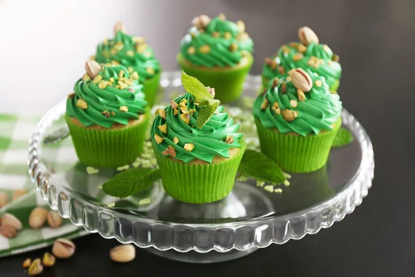 Pistachio cupcakes and mint leaves on glass stand — Stock Photo, Image