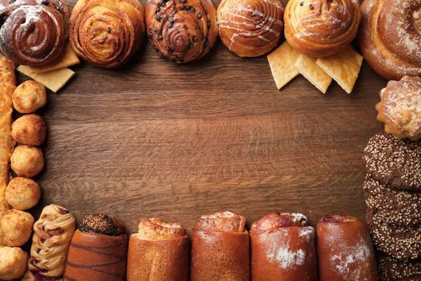 Bingkai berbagai macam kue segar pada latar belakang kayu — Stok Foto