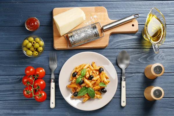 Leckere Penne-Pasta mit Zutaten auf Holztisch — Stockfoto