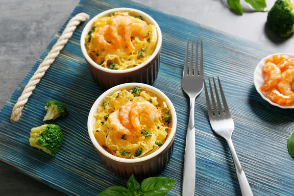 Gedeelten van de heerlijke pasta met garnalen op blauwe houten bord — Stockfoto