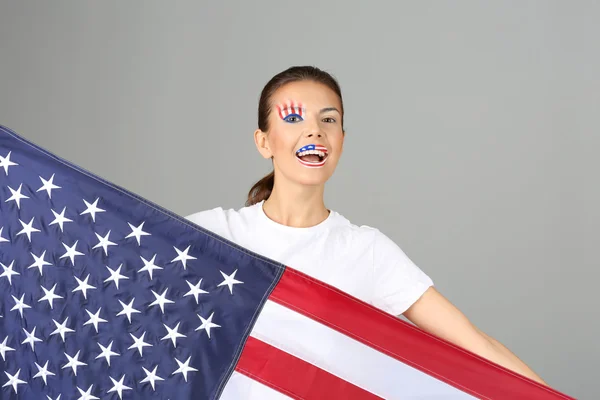 Girl with USA makeup and flag on grey background — Stock Photo, Image