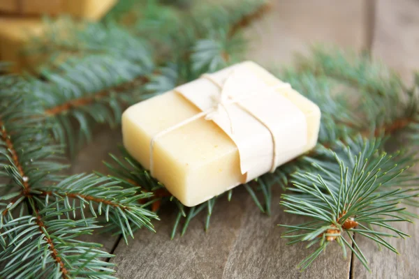 Piece of coniferous soap and branches on wooden background, close up view — Stock Photo, Image