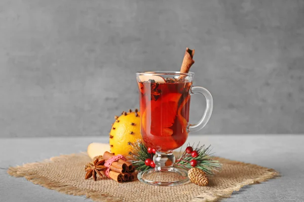 Glass cup of delicious mulled wine with Christmas decor on sackcloth — Stock Photo, Image