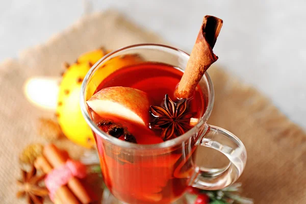 Copo de vidro de vinho delicioso Natal mulled em pano de saco, close-up — Fotografia de Stock