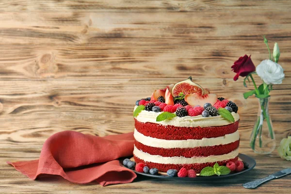 Chutný dort s ovocem a květiny na dřevěné pozadí — Stock fotografie