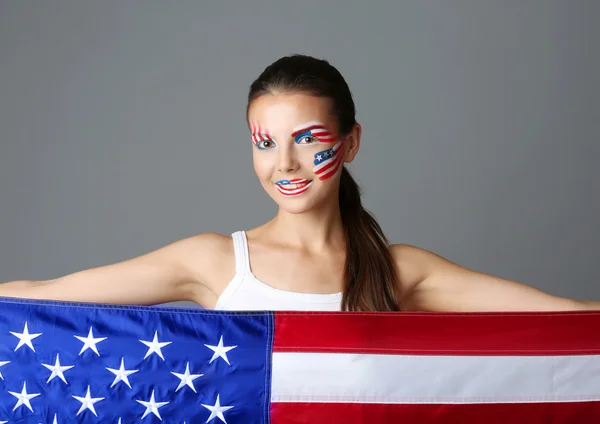 Flicka med Usa smink och flaggan på grå bakgrund — Stockfoto