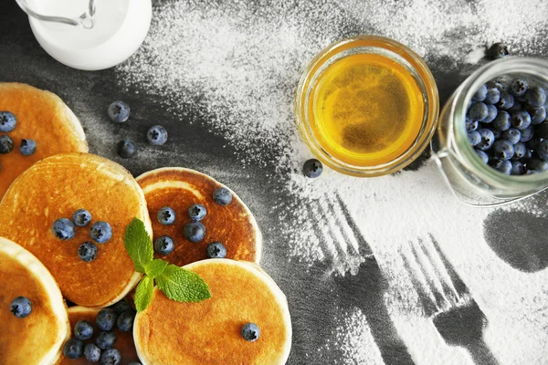 Scattered powdered sugar with delicious pancakes and blueberries, closeup — Stock Photo, Image