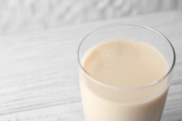 Vaso de sabrosa leche sobre mesa de madera blanca, vista de cerca — Foto de Stock