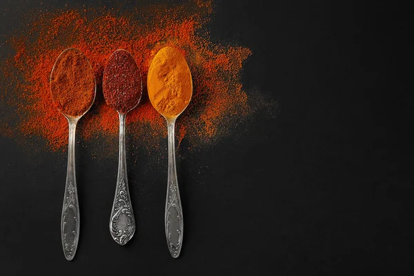 Karanlık bir arka plan üzerine kaşık içinde baharatlar