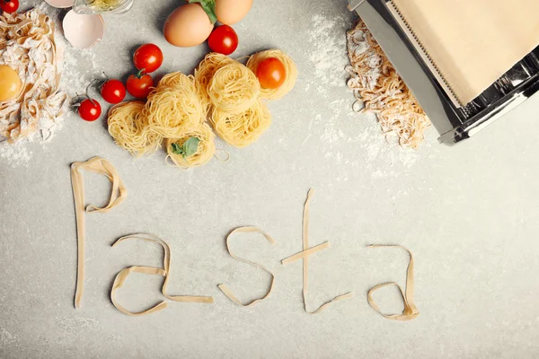Producten en word Pasta gemaakt van tagliatelle op keukentafel — Stockfoto