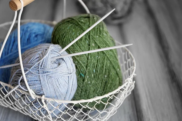 Metal basket with yarn and needles on wooden surface — Stockfoto