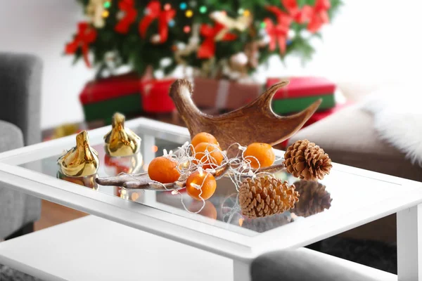 Mandarinas y conos en la mesa en la habitación decorada —  Fotos de Stock