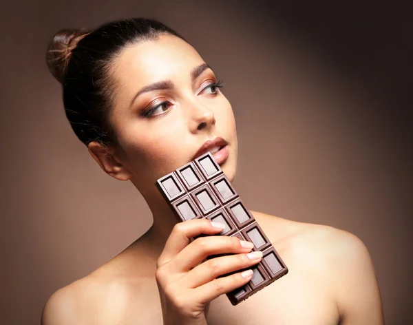 Beautiful girl with chocolate on brown background — Stock Photo, Image