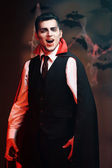 junger Mann als Vampir auf einer Halloween-Party auf dunklem Hintergrund