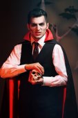 junger Mann als Vampir auf einer Halloween-Party auf dunklem Hintergrund
