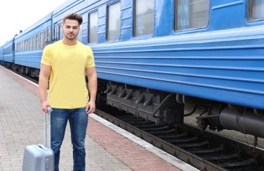 Demiryolu Platformu ile bavul üzerinde boş t-shirt duran genç adam