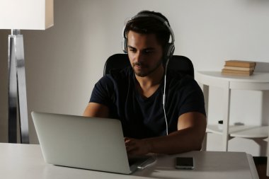 Müzik ve dizüstü bilgisayarda çalışan yakışıklı adam