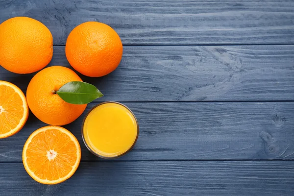 Oranges with juice on wooden table — Stock Photo, Image