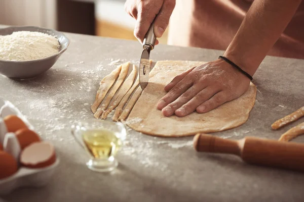 Male hands preparing pasta on kitchen table — Stock Photo, Image