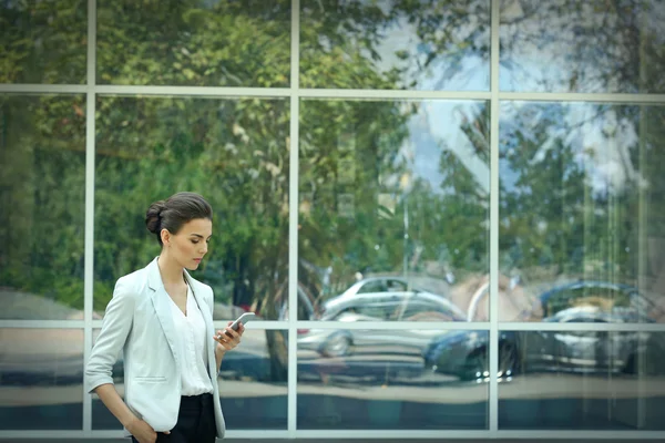 Hermosa mujer de negocios con teléfono en el fondo de la ventana —  Fotos de Stock